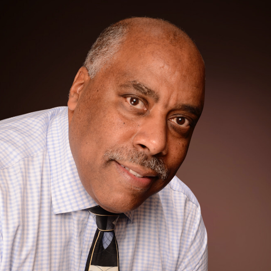 Professional headshot of William Churchhill, a smiling Black man in a white shirt with blue lines, and patterned beige, black and grey tie, against a brown background